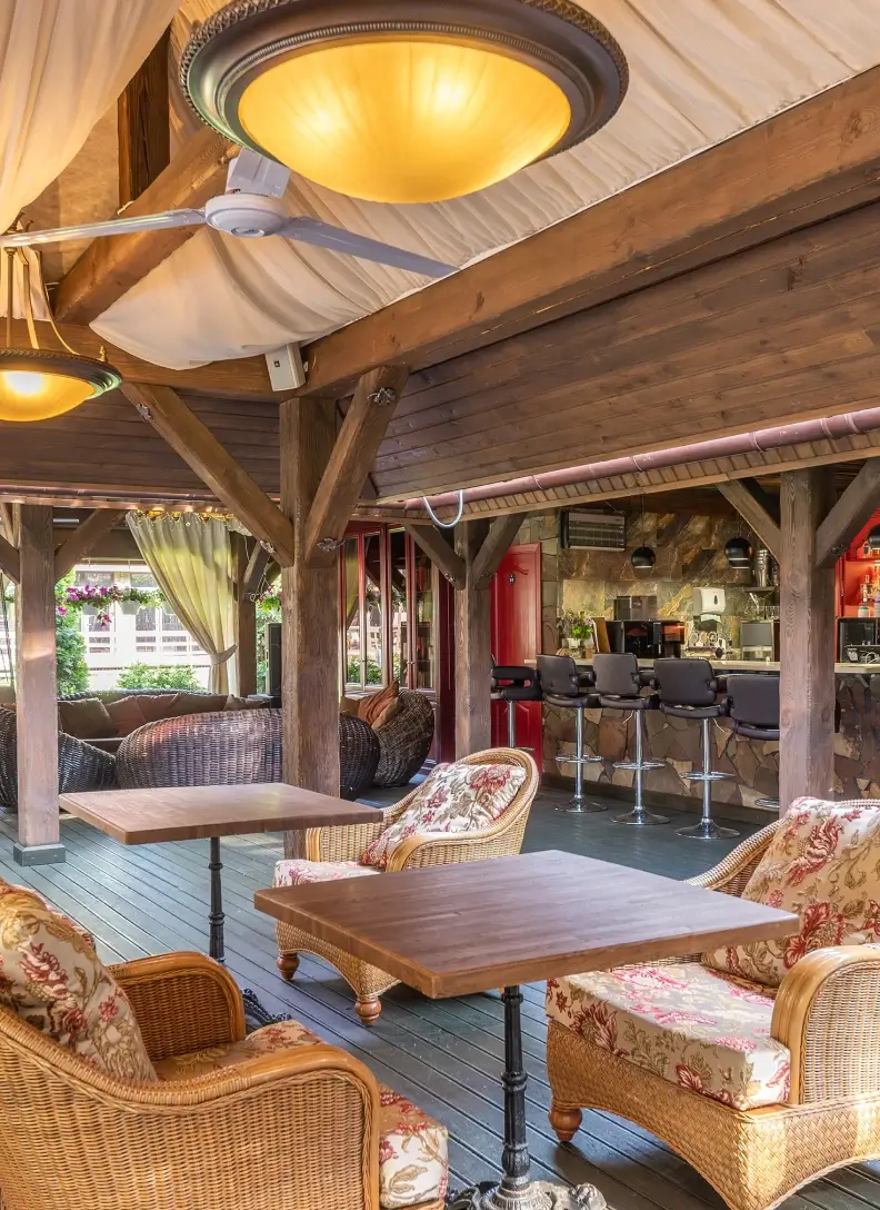 Covered outdoor patio bar with wicker seating, wooden tables, and rustic bar area